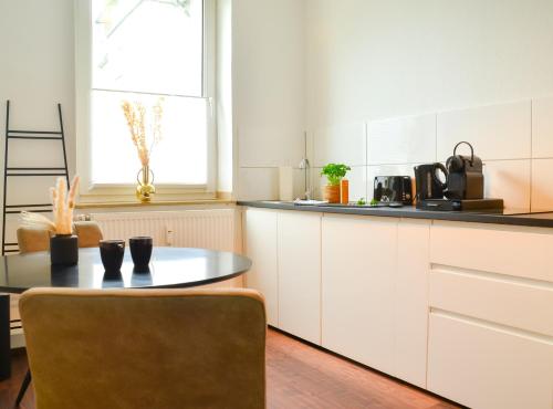 een keuken met witte kasten en een tafel bij MILPAU Buer 3 - Modernes und zentrales Premium-Apartment mit Queensize-Bett, Netflix, Nespresso und Smart-TV in Gelsenkirchen