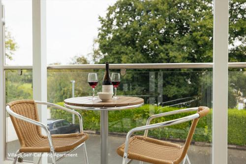 a table with two glasses of wine on a balcony at St Brides Spa Hotel & Village Apartments in Saundersfoot