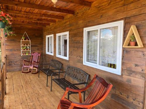 a porch of a log cabin with chairs and windows at Cabaña Aurora – COZY Cabin with an Amazing view! in San Pablo
