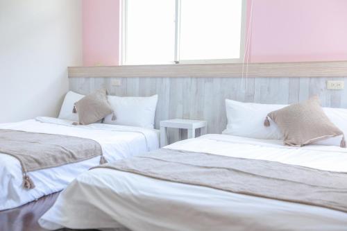 two beds in a room with white sheets and pillows at 綠島小巷 微光南寮館 in Green Island