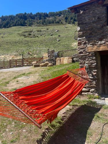 a red hammock sitting next to a stone building at Borda Martí, Chalet de montaña en la Vall d'Incles HUT1-08422 in Canillo