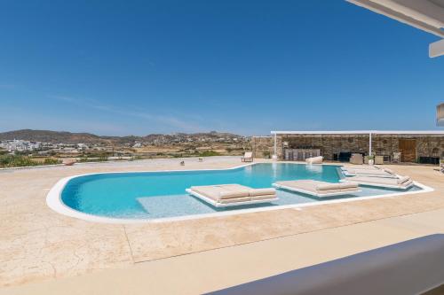 a villa with a swimming pool with lounge chairs at Blu Suites and Studios in Adamas