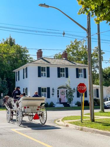 a horse drawn carriage in front of a white house at Beautiful Historic Luxury Getaway in Niagara-on-the-Lake