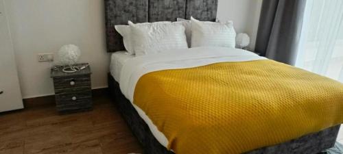 ein Schlafzimmer mit einem großen Bett und einer gelben Decke in der Unterkunft Novarite King in Nairobi