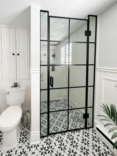 a bathroom with a toilet and a glass shower door at Beautiful Historic Luxury Getaway in Niagara-on-the-Lake