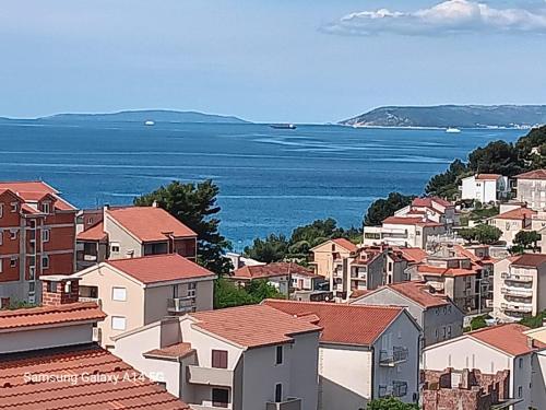 a town with houses and the ocean in the background at Apartman Palma and Luxury Penthouse for a family with swiming pool,parking,terrace,panoramic view at the sea,Podstrana in Podstrana