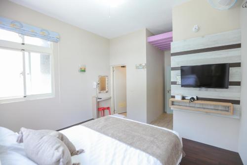 a bedroom with a bed and a tv on a wall at 綠島小巷 微光南寮館 in Green Island