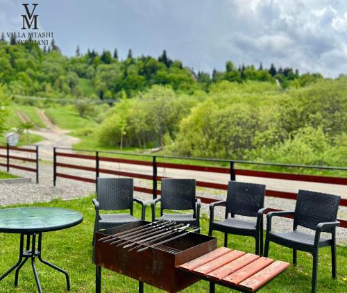 a picnic table and chairs and a table and a bench at Villa Mtashi in Bakuriani