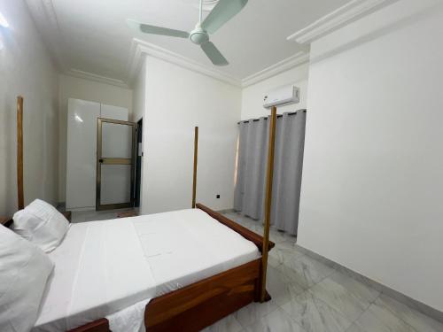 a white bedroom with a bed and a ceiling at Luxe Club in Cotonou