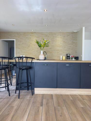 une cuisine avec des placards bleus et des tabourets de bar dans l'établissement Maison Familiale Moderne avec Grand Jardin à Bommes - Un Havre de Paix pour vos Vacances, à Bommes