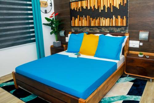 Schlafzimmer mit einem Bett mit blauen und gelben Kissen in der Unterkunft La pépite in Cotonou