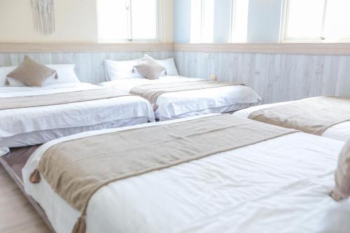 a group of four beds in a room with windows at 綠島小巷 微光南寮館 in Green Island