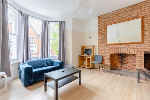 een woonkamer met een blauwe bank en een stenen open haard bij Roomy 3BD by Hampstead Heath! in Londen