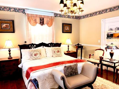 a bedroom with a large bed and a chair at Grape Suite-heart of oldtown in Niagara on the Lake