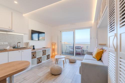 een keuken en een woonkamer met een bank en een tafel bij La parenthèse - Studio vue Océan avec terrasse, plage Notre-Dame in Capbreton