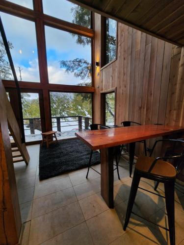 a large wooden table in a room with windows at Lodge Rincon del Bosque, Malalcahuello in Malalcahuello