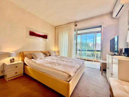 une chambre avec un grand lit et une grande fenêtre dans l'établissement B038 Spacieux Appartement proche Croisette parking, à Cannes