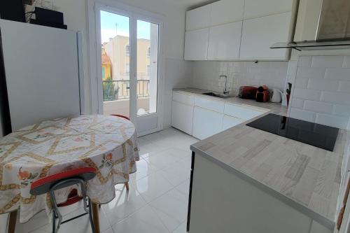 une cuisine blanche avec une table et une fenêtre dans l'établissement Apartment in the heart of Saint-Raphaël, à Saint-Raphaël