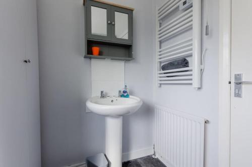 a white bathroom with a sink and a mirror at Hullidays 3 bed House Hull West Calvert in Hull