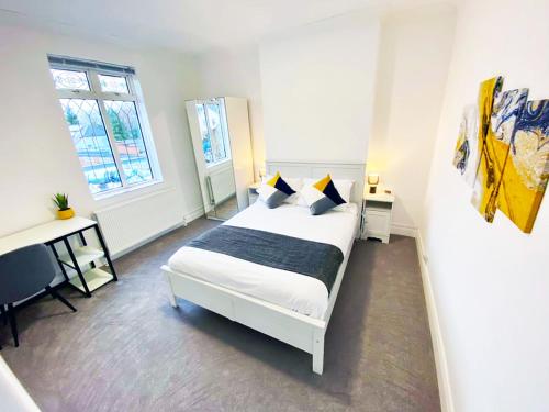 a bedroom with a bed and a desk and a window at Modern 2/3 huge bedrooms Heathrow & Central London in Feltham
