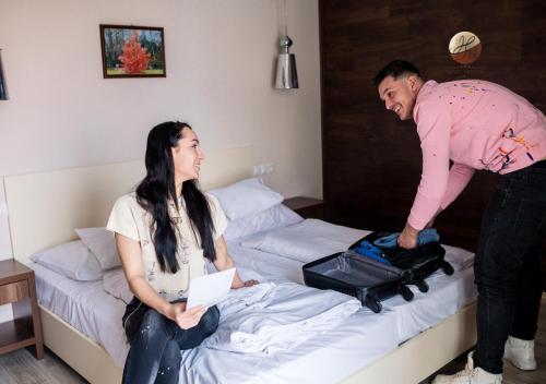 een man en een vrouw die naast een bed staan bij Hotel Median Hajdúnánás in Hajdúnánás