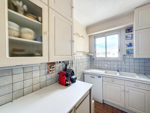 une cuisine avec des placards blancs et un comptoir blanc dans l'établissement 3p TERRASSE CANNES PROCHE CROISETTE, à Cannes