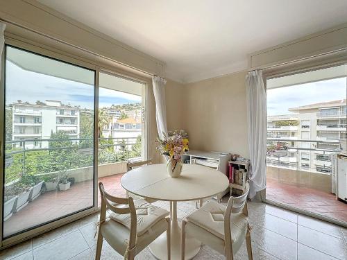 - une salle à manger avec une table, des chaises et de grandes fenêtres dans l'établissement 3p TERRASSE CANNES PROCHE CROISETTE, à Cannes