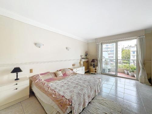 une chambre avec un lit et une grande fenêtre dans l'établissement 3p TERRASSE CANNES PROCHE CROISETTE, à Cannes