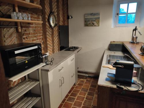 une cuisine avec un évier et un micro-ondes dans l'établissement La Coquerie, à Fondettes