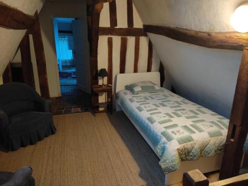 une chambre avec un lit et une chaise dans une pièce dans l'établissement La Coquerie, à Fondettes