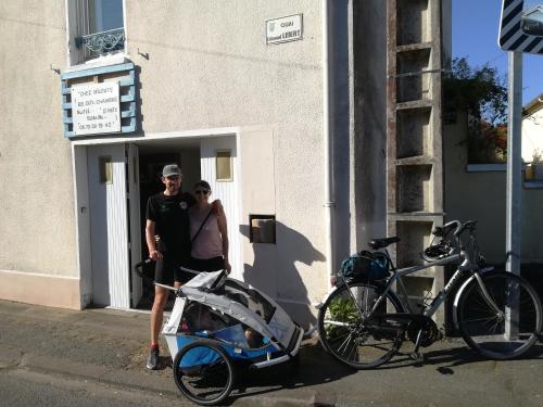 a man and a woman standing outside a building with a bike at Miloute à la Montagne in Bagnères-de-Bigorre
