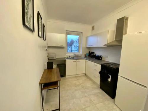 a kitchen with a refrigerator and a table in it at Modern 2/3 huge bedrooms Heathrow & Central London in Feltham
