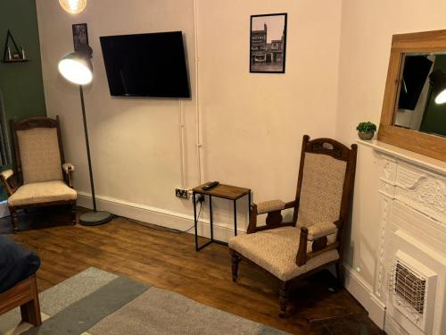sala de estar con 2 sillas y TV de pantalla plana en Premium Dighbeth en Birmingham