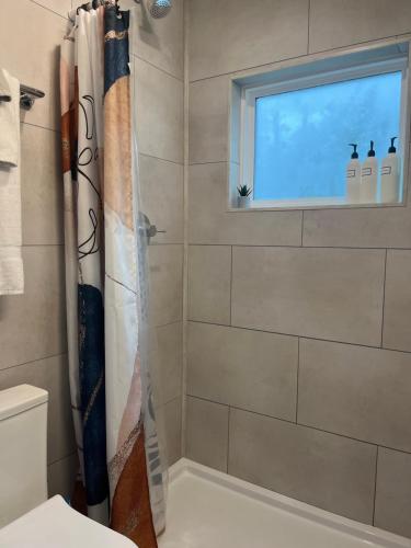 een badkamer met een douchegordijn en een raam bij The Overlook Tiny Home in Elizabethtown