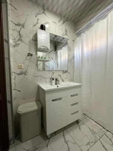a white bathroom with a sink and a mirror at Rustaveli Apartment 113 in Kutaisi
