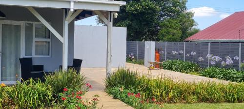 a house with a fence and a garden with flowers at Mosswood Bed & Breakfast in Graskop
