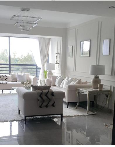 a living room with white furniture and a large window at River sweet-conner in Nairobi