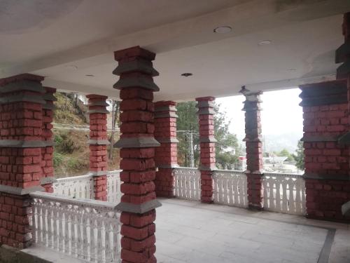 balkon z kolumnami z czerwonej cegły i białym płotem w obiekcie Luxury Sunset Villa w mieście Abbottabad
