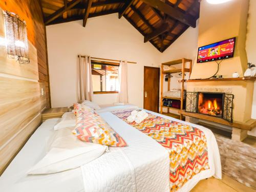 Chalés Galinha Da Roça في مونتي فيردي: غرفة نوم بسرير ومدفأة