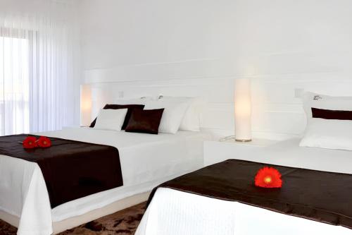 um quarto branco com 2 camas com flores vermelhas em 2 bedrooms house with terrace and wifi at Riba de Mouro em Riba de Mouro