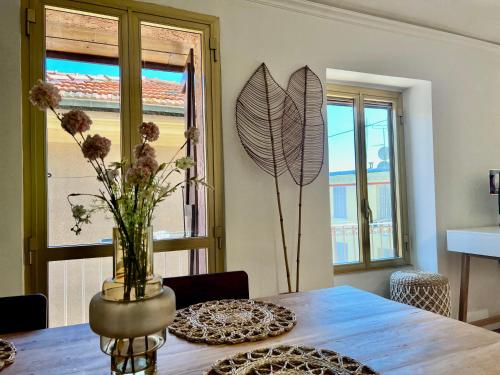 une table de salle à manger avec un vase de fleurs dessus dans l'établissement Renovated House In The Center Of Beausoleil, à Beausoleil