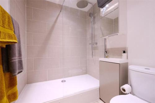 a bathroom with a shower with a toilet and a sink at Chic & Modern Flat: Perfect for Exploring Kent! in Kent