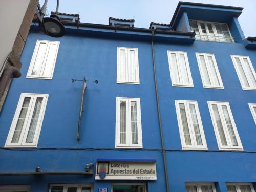 een blauw gebouw met witte ramen en een kruis bij Isabel in Cudillero