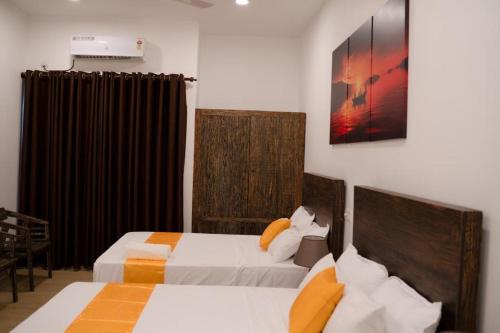 een slaapkamer met 2 bedden en een schilderij aan de muur bij Lucky Transit Hotel in Katunayaka