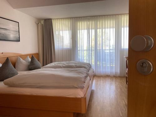 a bedroom with a bed and a large window at Appartementhotel Röhrenbach in Immenstaad am Bodensee