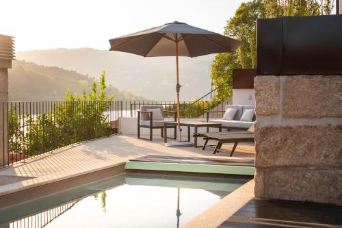 a pool with an umbrella and some chairs and a table at Feel Discovery Casa de Cima Douro Valley in Riba Douro