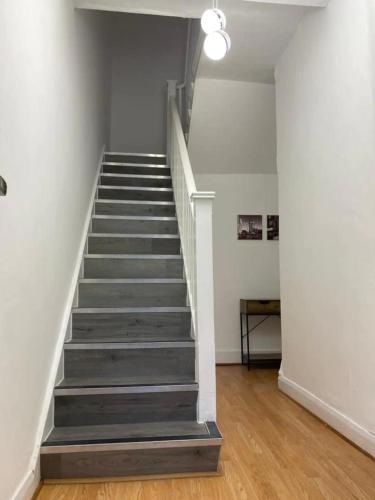 a staircase in a room with white walls and wood floors at Modern 2/3 huge bedrooms Heathrow & Central London in Feltham