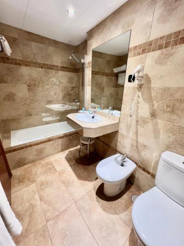 a bathroom with a toilet and a sink and a tub at Carlos V Malaga in Málaga