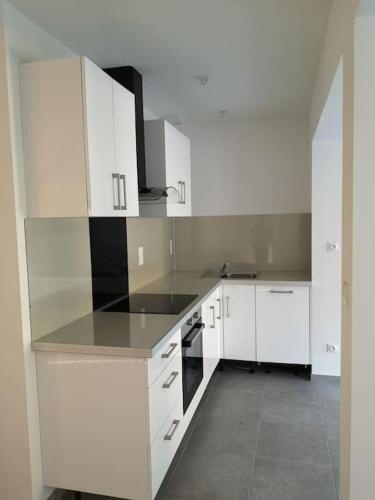 a white kitchen with white cabinets and appliances at Maison 6 personnes spacieuse proche Astérix in Pontpoint