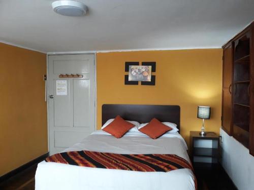 Sumaq Wasi Barranco II في ليما: غرفة نوم مع سرير ووسادتين برتقاليتين